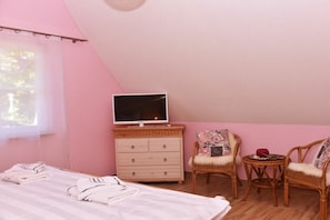A bedroom with a bed, a dresser, a television, two chairs, and a small table. - Holiday home with 2 bedrooms (Born auf dem Darß)