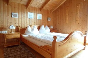 A wooden-paneled bedroom with a bed, nightstands, and wall-mounted pictures. - Waldmünchen Type B 1 (Waldmünchen)