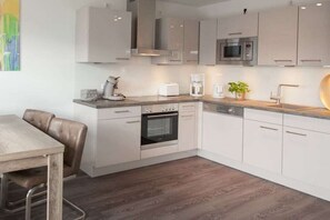 A modern kitchen with white cabinets, a built-in oven, a microwave, and a coffee maker. - Baltic Sea adventure (Scharbeutz)