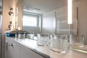 En köksbänk med flera genomskinliga glas och ett fönster i bakgrunden.