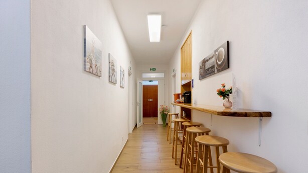 A hallway with wooden flooring, a coffee bar with stools, and framed artwork on the walls.