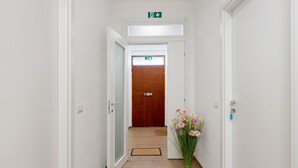 A hallway with white walls, wooden flooring, and a wooden door at the end.