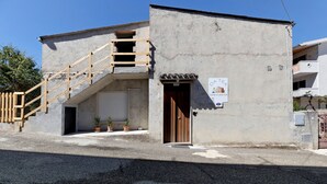 A building with a staircase leading to a landing, a closed garage door, and a sign indicating a tea house.