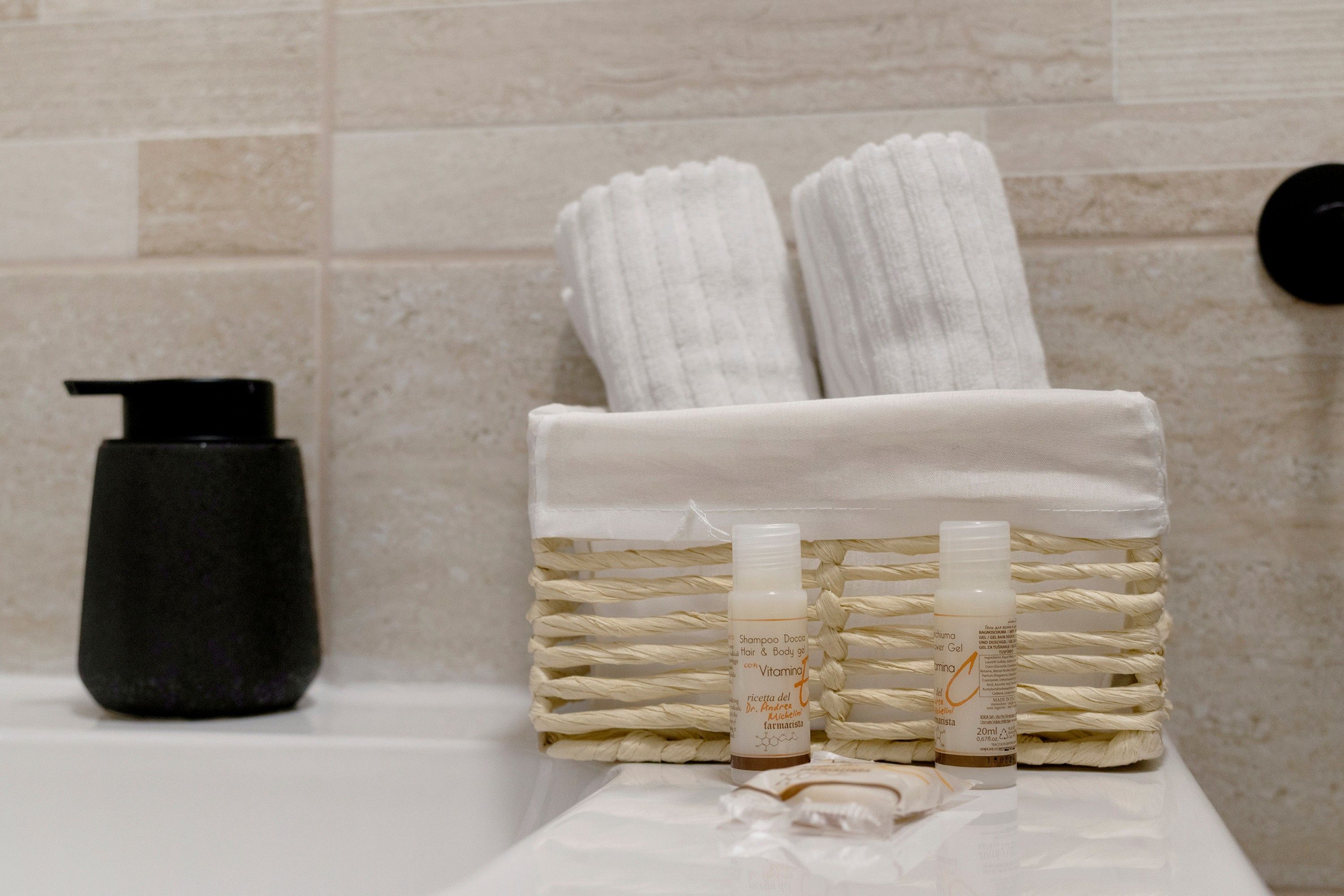 Een badkamer met een handdoekrek met twee handdoeken, een fles shampoo en een fles douchegel op een witte ondergrond.