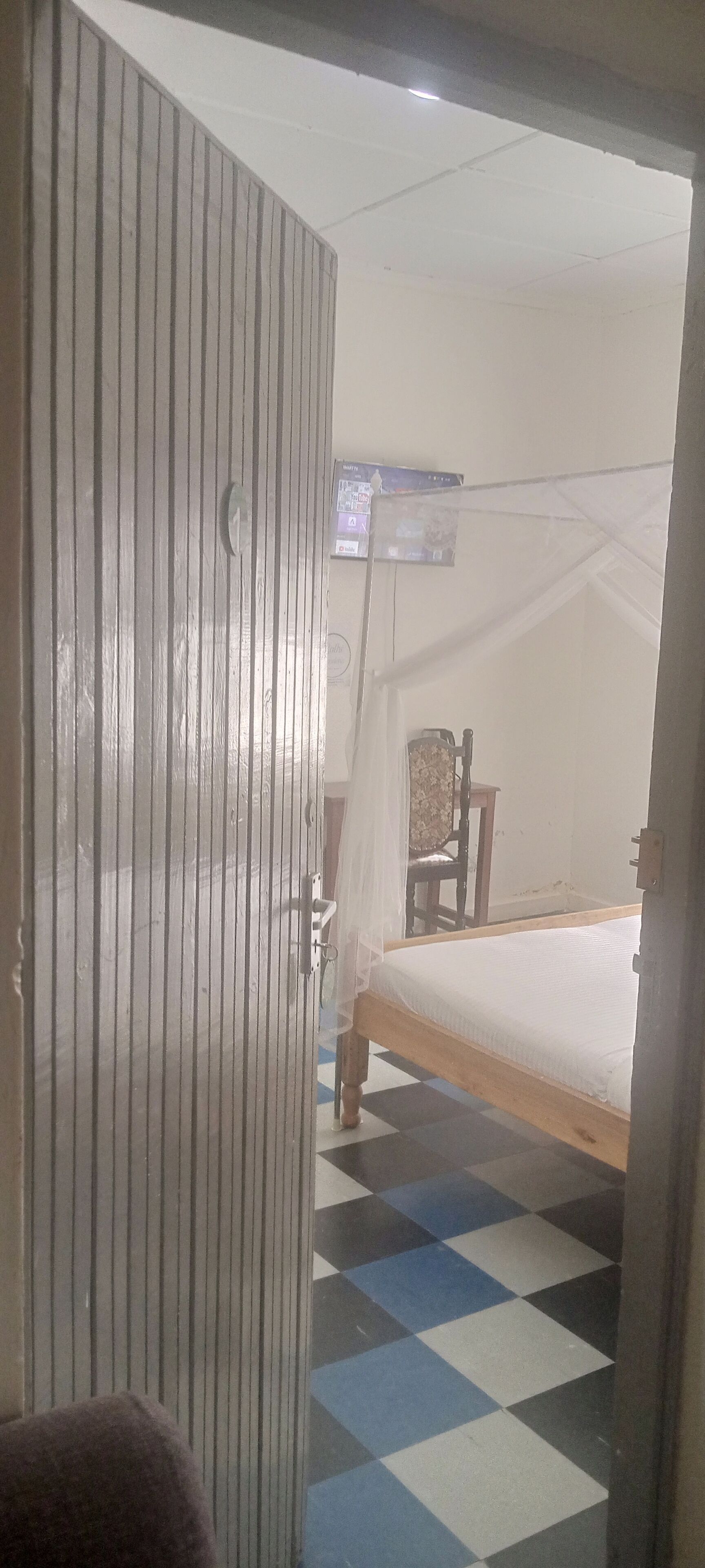 A room with a bed, a chair, and a mosquito net.
