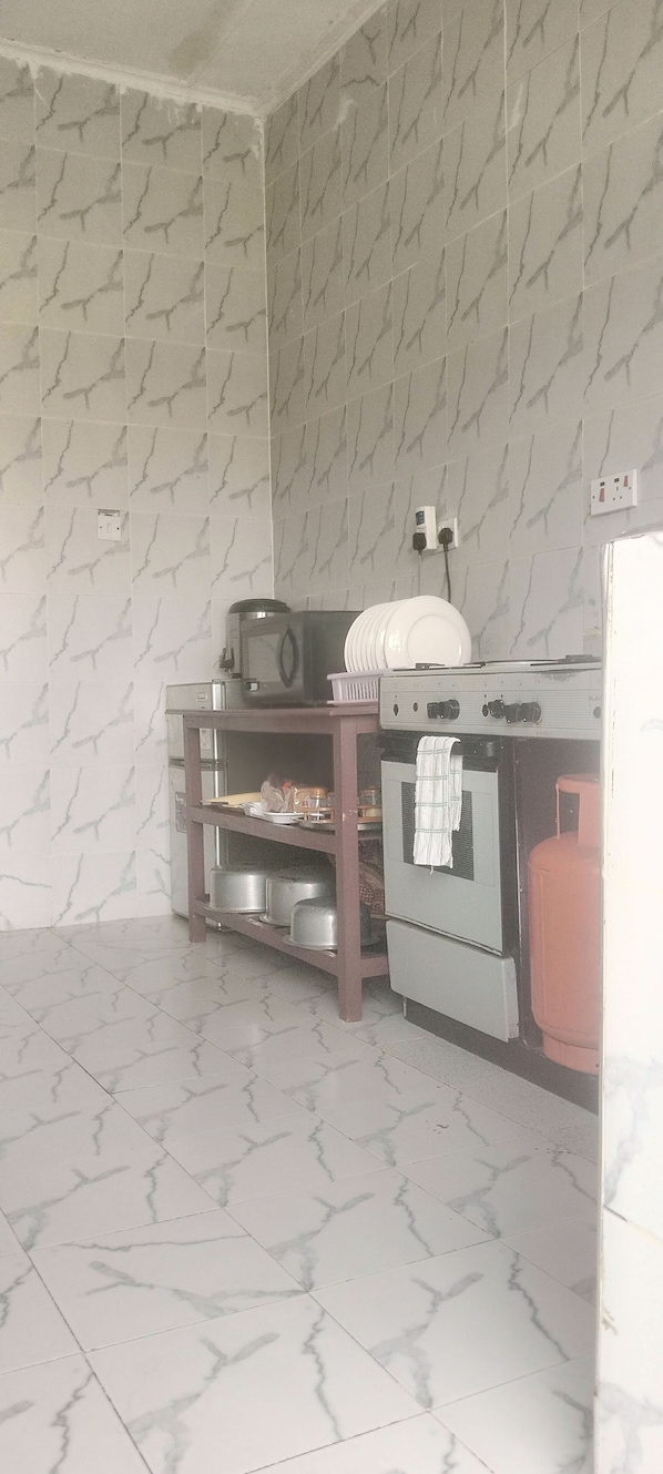 A kitchen with a tiled backsplash, a stove, a sink, and a countertop with various kitchen items.
