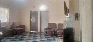 A room with a checkered floor, a sofa, a table, and two doors. - Bathi Gardens Retreat - Peaceful Naivasha Getaway in Nature (Naivasha)