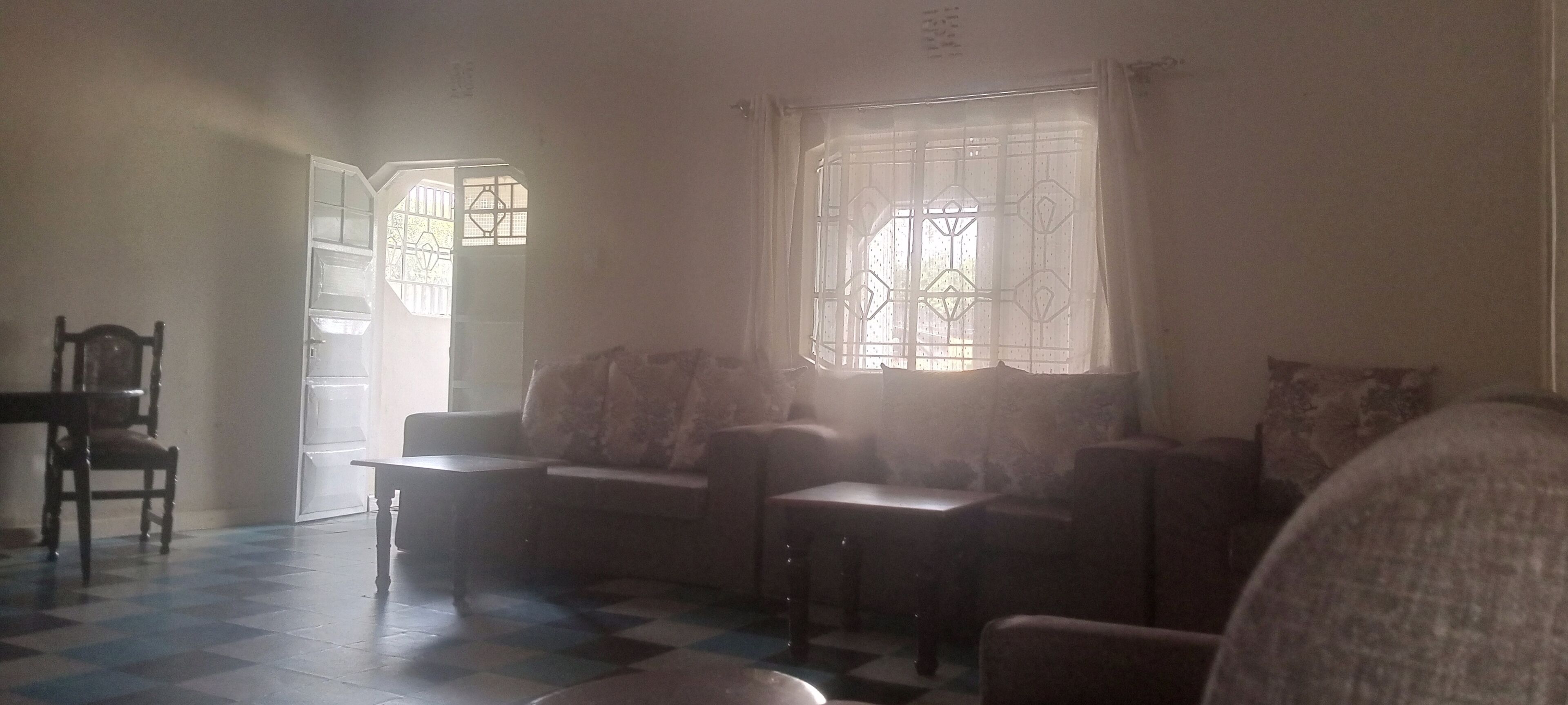 A room with a checkered floor, a sofa, a chair, and a table.