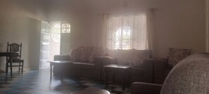 A room with a checkered floor, a sofa, a chair, and a table. - Bathi Gardens Retreat - Peaceful Naivasha Getaway in Nature (Naivasha)