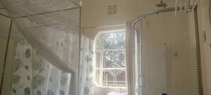 A bathroom with a window, a shower curtain with a leaf pattern, and a towel rack. - Bathi Gardens Retreat - Peaceful Naivasha Getaway in Nature (Naivasha)