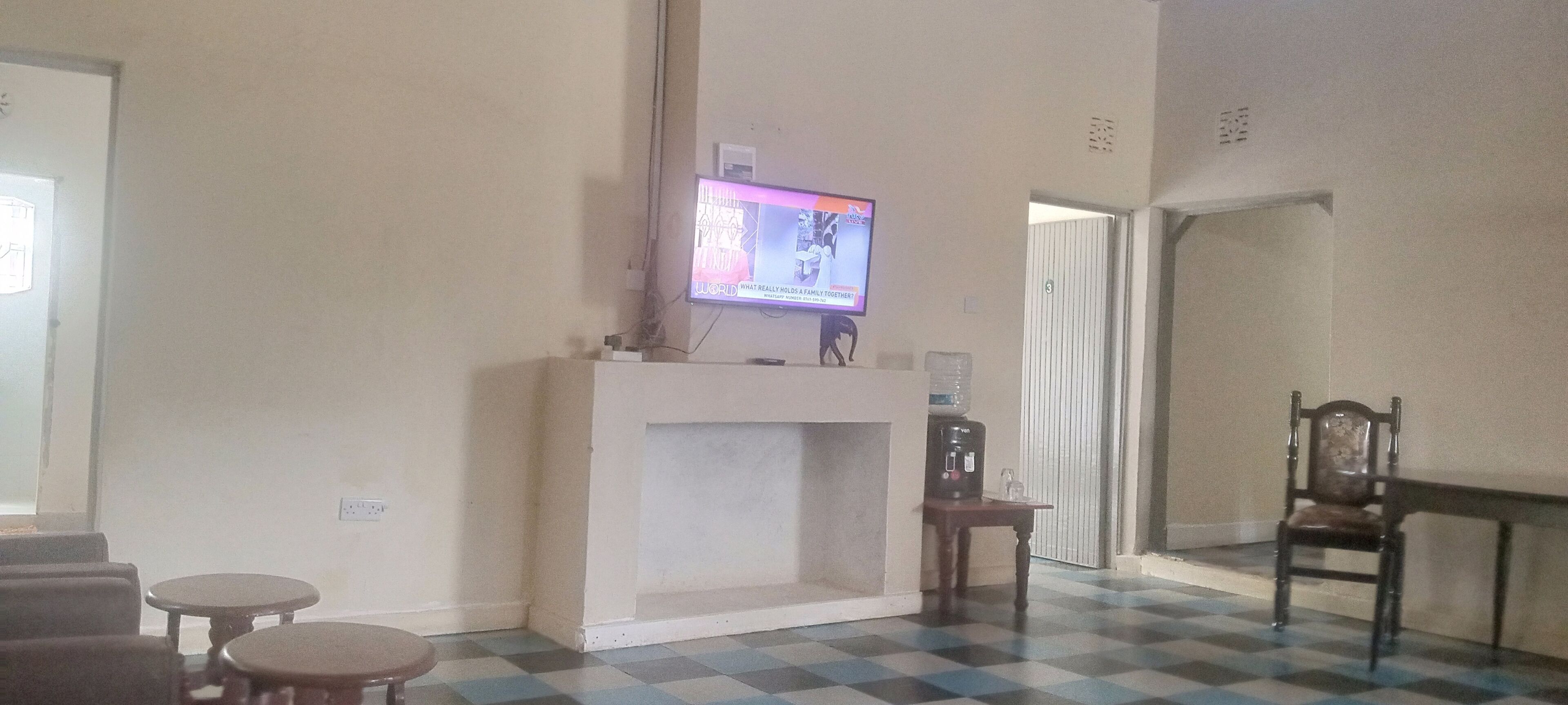 A living room with a fireplace, a television mounted above it, and a checkered floor.
