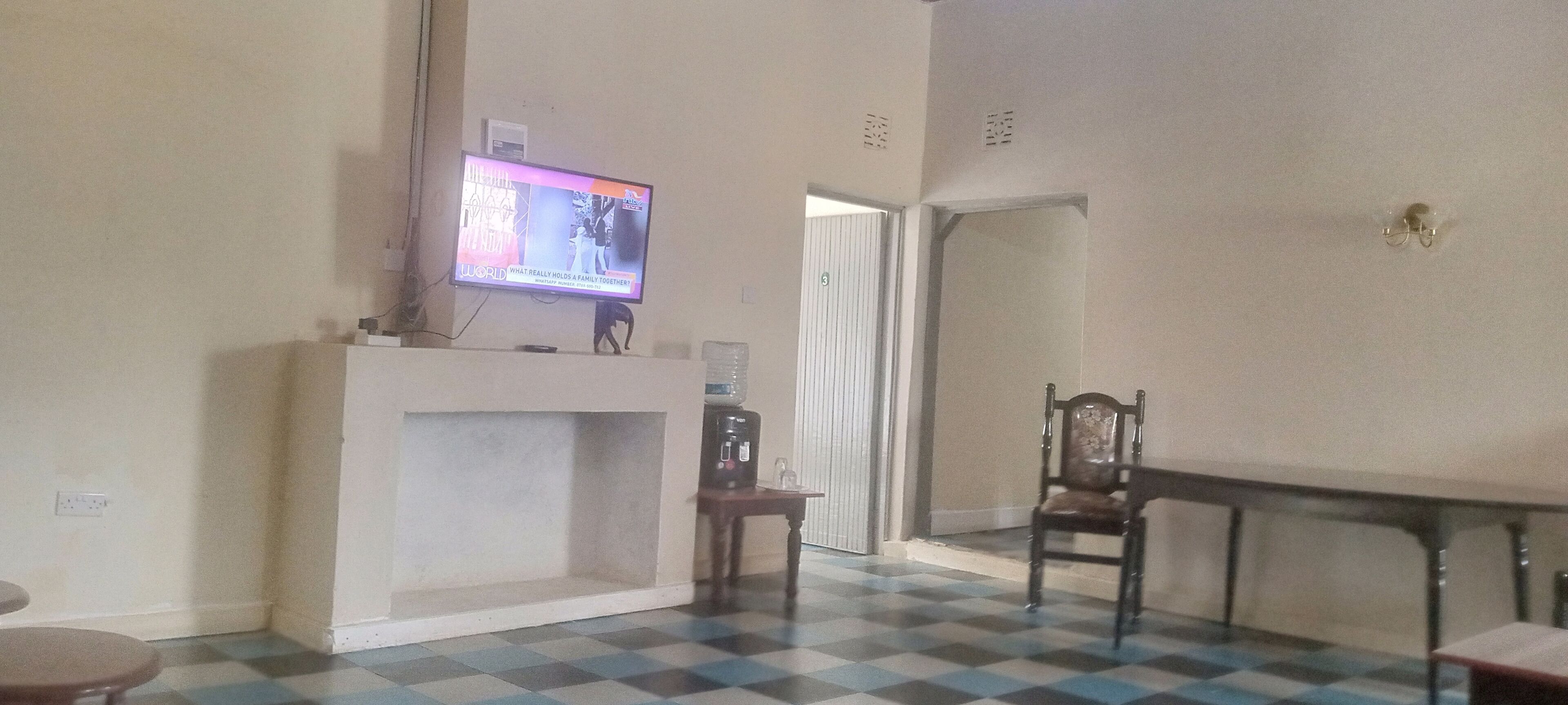 Een kamer met een aan de muur bevestigde televisie, een open haard, een eettafel en een stoel.