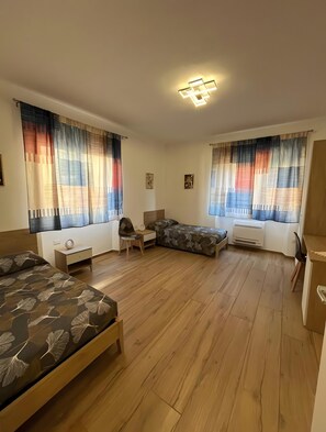 Una camera da letto con due letti, una scrivania, una sedia e una finestra con tende.