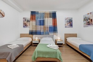 A room with two single beds, a central bed, and a headboard with a light fixture.