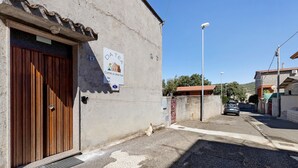 A narrow street with a building featuring a wooden door and a sign with a house icon.