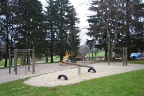 Ein Spielplatz mit Schaukeln, einer Wippe und Klettergerüsten.