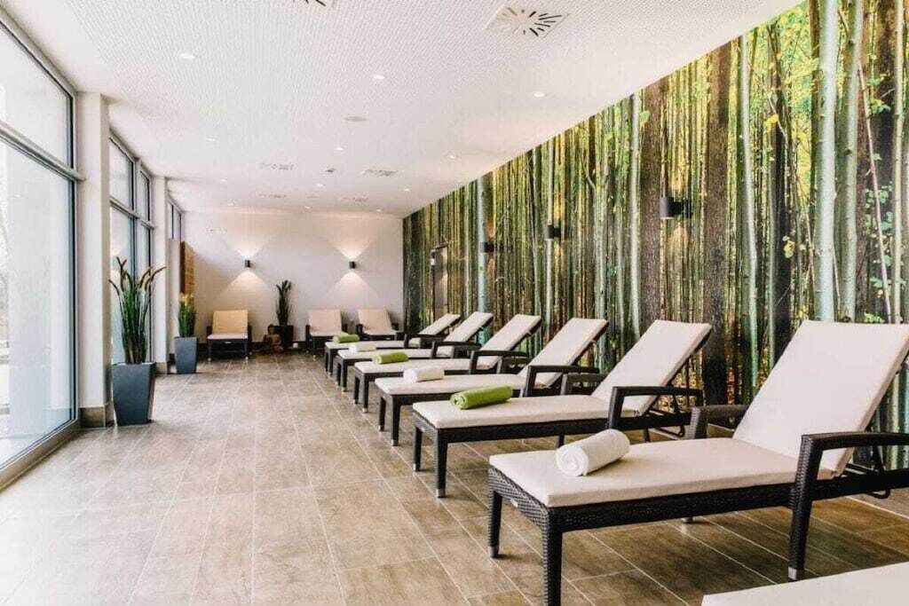 Ein Wellnessbereich mit Liegestühlen, einer Wand mit vertikalen Streifen und einem Fliesenboden.