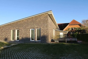 Een bakstenen gebouw met een schuin dak, een verharde oprit en een keurig onderhouden gazon.