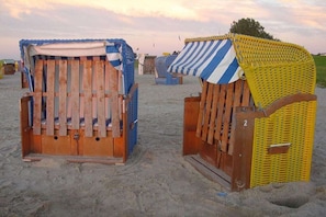 Strandhutten met houten frames en stoffen kappen, gelegen op een zandstrand.