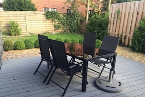 Een terras buiten met een tafel en vier stoelen.