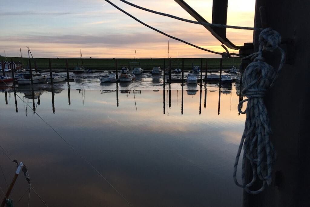 Un port de plaisance avec des bateaux amarrés, une eau calme et une corde attachée à un poteau.