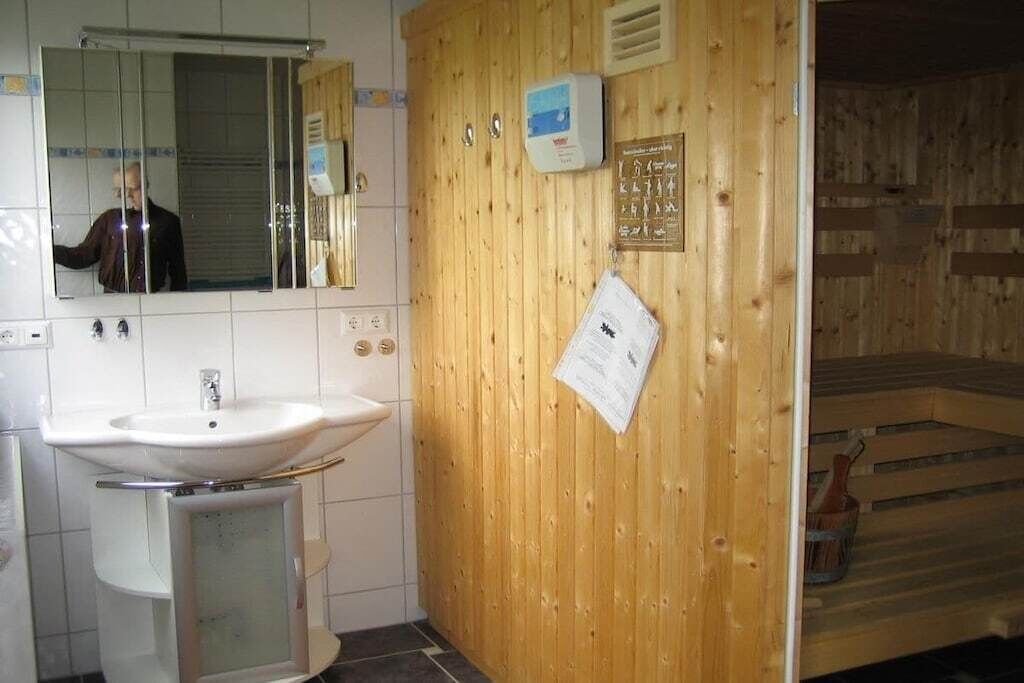 A bathroom with a white sink, mirror, and wooden paneling.