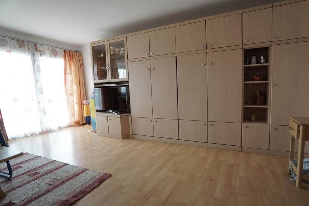 Ein Zimmer mit großem Kleiderschrank, Fernseher und einem fenster mit Vorhängen.