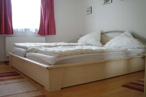 Ein Einzelbett mit weißer Bettwäsche, einem Holzrahmen und einem Heizkörper darunter.