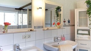A bathroom with two sinks, a large mirror, and a cabinet with towels. - Holiday home with 1 bedroom (Groß Zecher)
