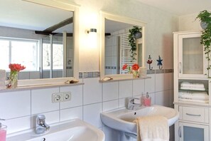 A bathroom with two sinks, a large mirror, and a cabinet with towels. - Holiday home with 1 bedroom (Groß Zecher)