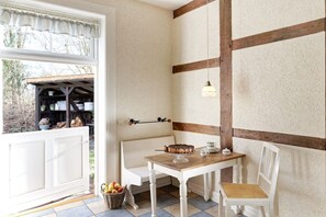A room with a white bench, a wooden table, and a hanging light fixture. - Holiday home with 1 bedroom (Groß Zecher)