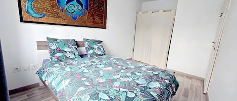 A bedroom with a bed, a nightstand, a wall-mounted artwork, and a wardrobe.