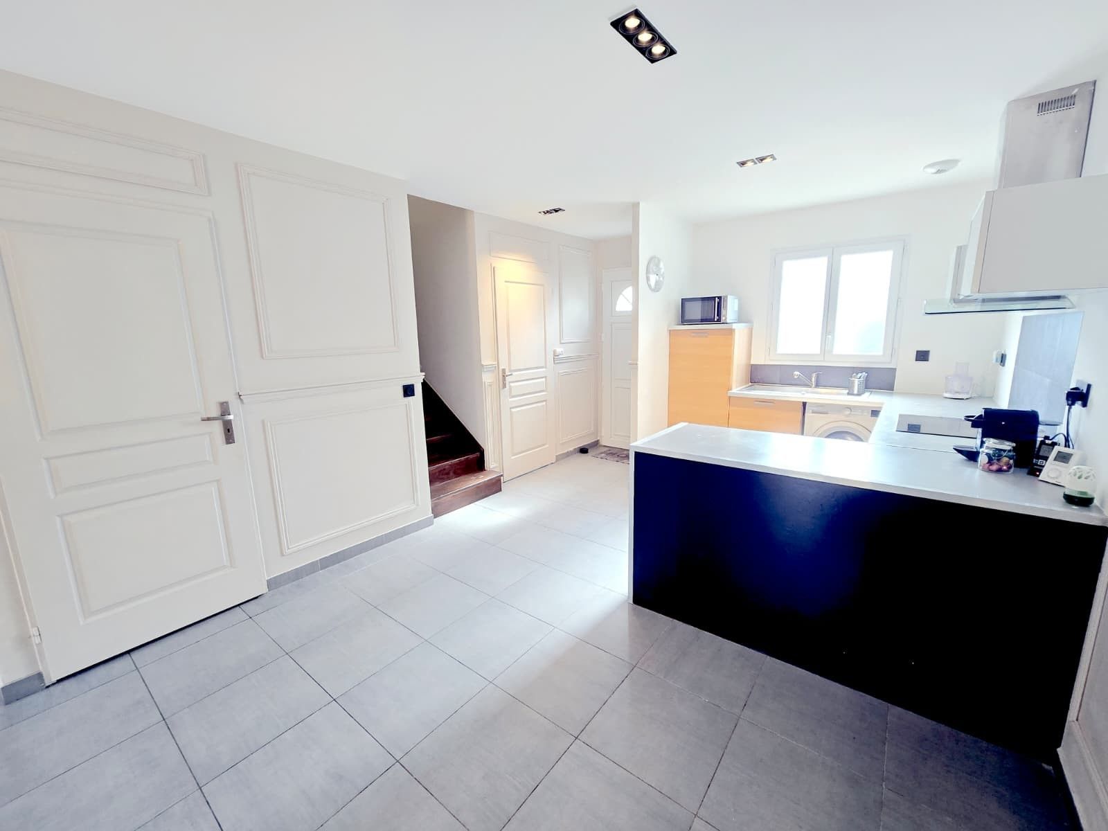 Een moderne keuken met een centraal eiland, witte kasten en een magnetron.