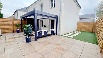 Un patio couvert aménagé avec des sièges et une plante en pot.