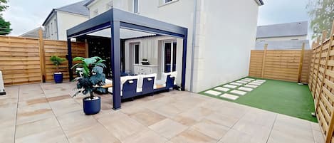 A covered patio area with a seating arrangement and a potted plant.
