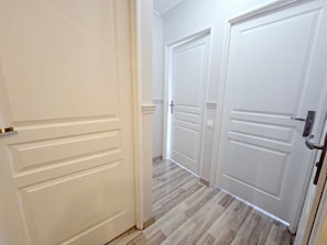 Un pasillo con puertas blancas y suelo de madera.