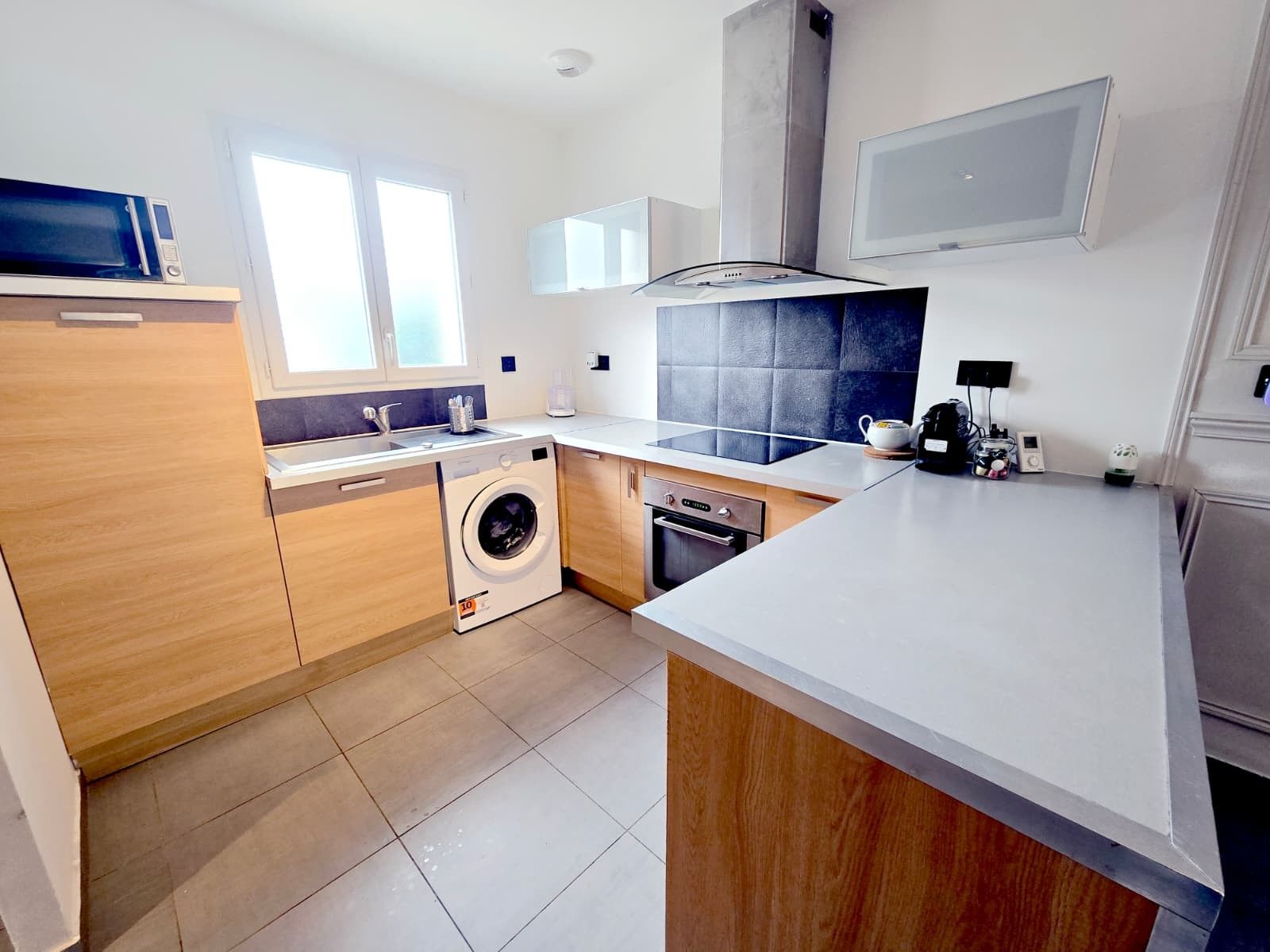 A modern kitchen with a built-in washing machine, a dishwasher, and a microwave.