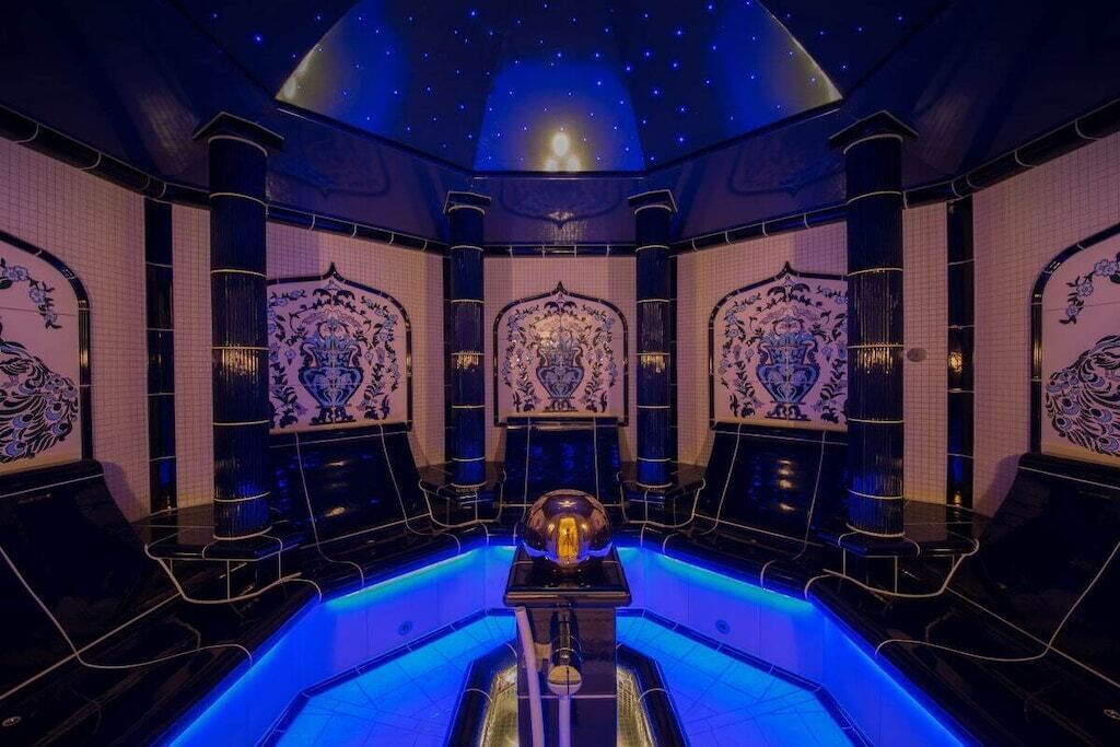 Een luxe kamer met een sterrenhemelplafond, gedetailleerde muurdecoraties en een centraal sferisch object.