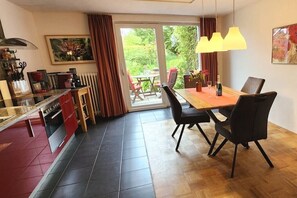 Eine moderne Küche mit Essbereich, Blick durch eine Glastür und einem mit Stühlen gedeckten Tisch.