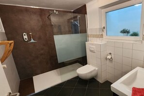 Un baño moderno con ducha envuelta en vidrio, inodoro blanco y bañera.