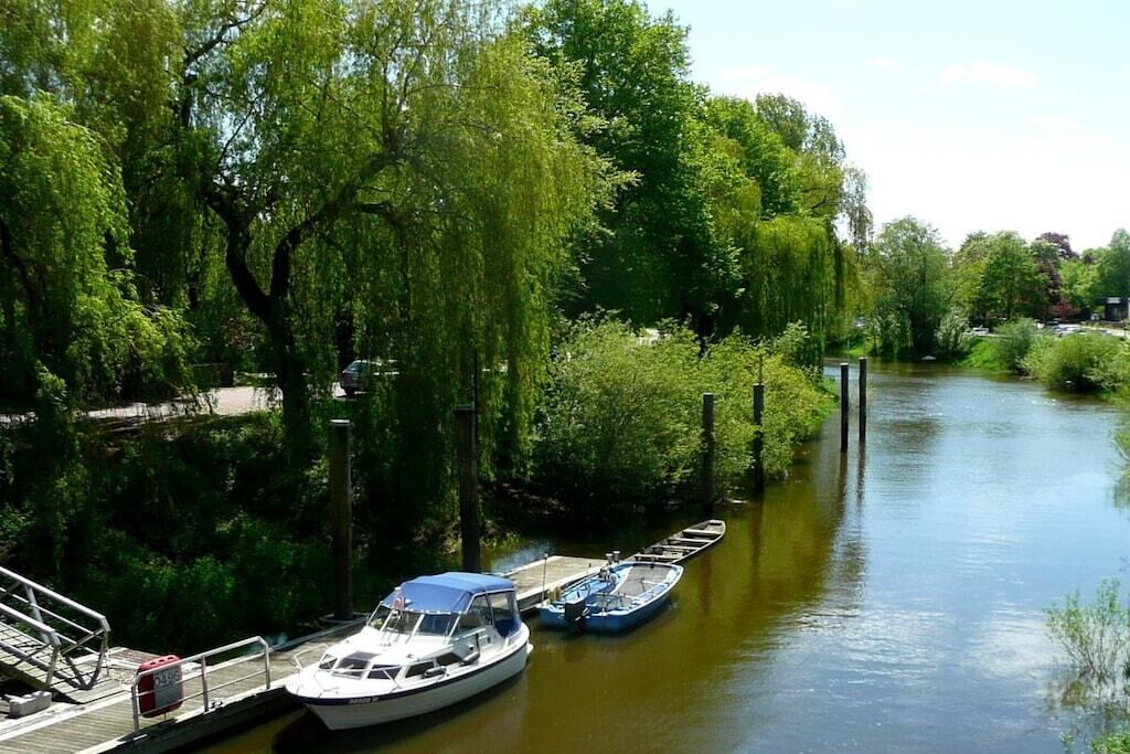 Ein Fluss mit vertäuten Booten links, umgeben von üppigem Grün.