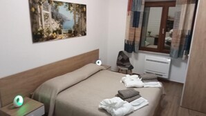 A hotel room with a bed, a bedside table with a lamp, a painting on the wall, and a window with curtains. - Room Da Tea - Rooms with shared bathroom, mountain view, Wi-Fi, air conditioning (Olzai)