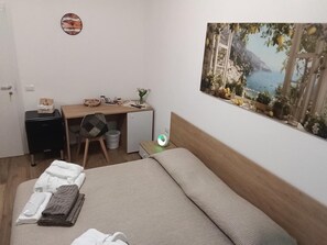 A bedroom with a bed, a desk, a chair, a small cabinet, and a wall-mounted clock. - Room Da Tea – Rooms with Shared Bathroom, Mountain View, Wi-Fi and Air Conditioning (Olzai)