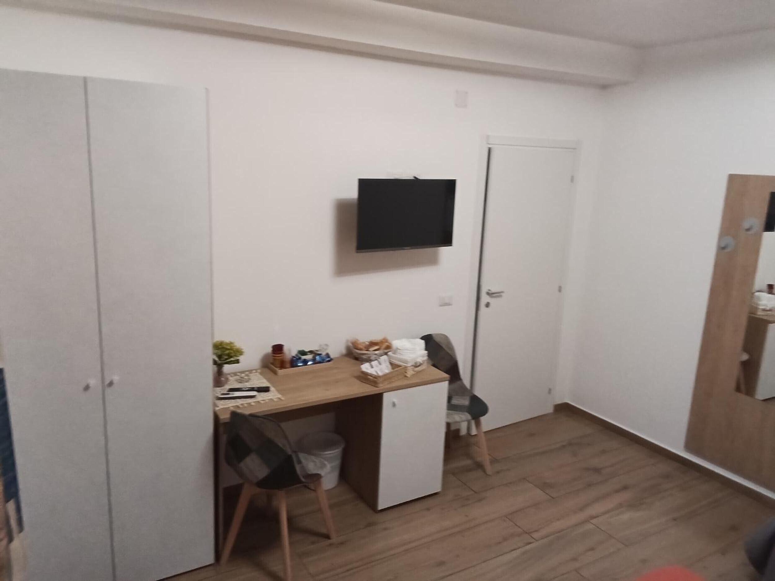 A small room with a desk, chair, and a television mounted on the wall.