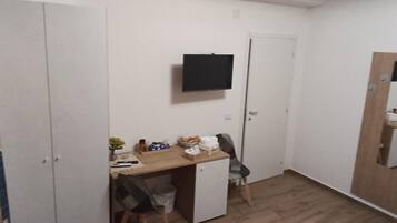 A small room with a desk, chair, and a television mounted on the wall.