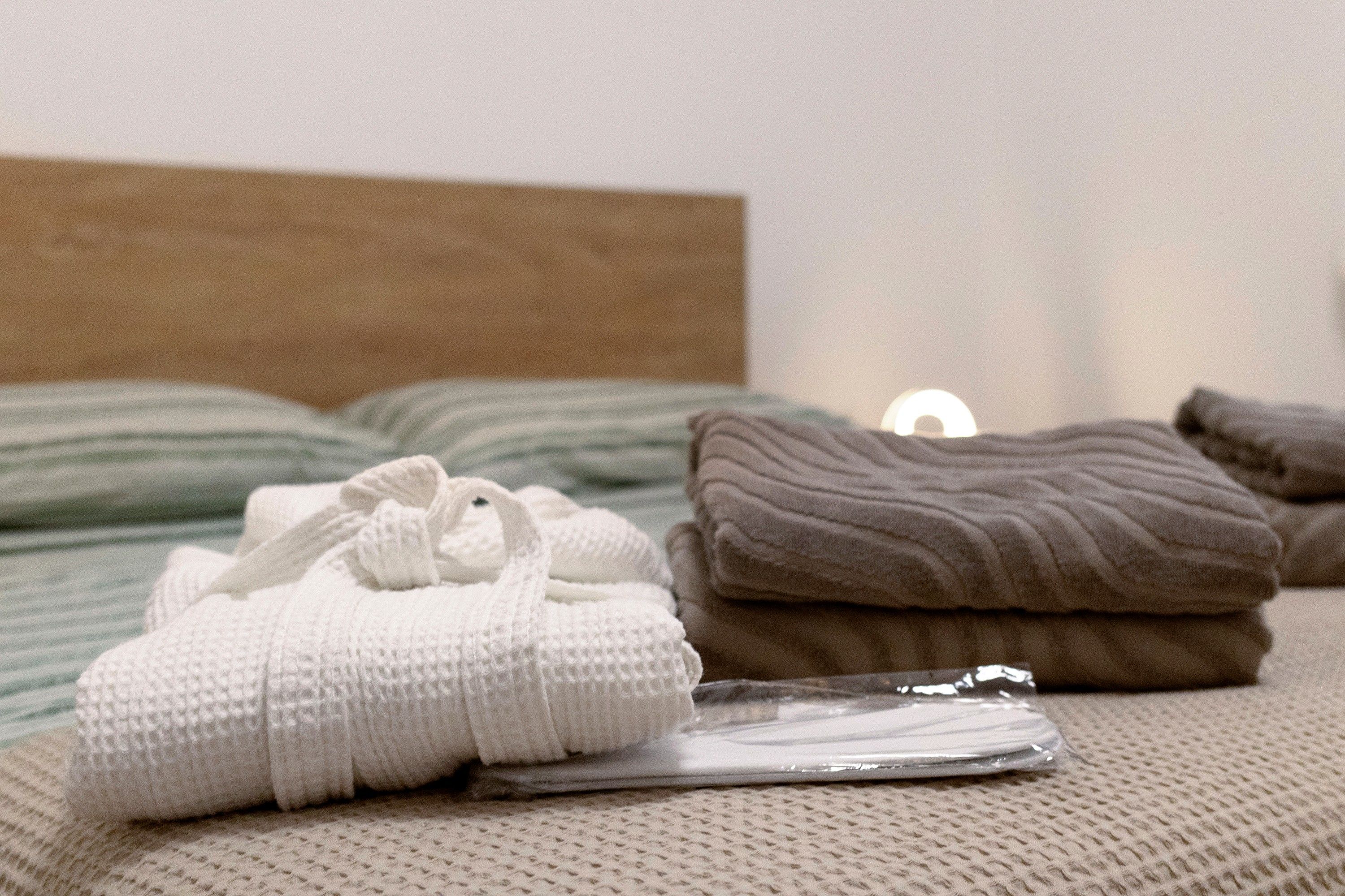 A neatly made bed with a headboard, a white knitted item on the bed, and a brown pillow.