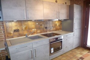 A kitchen with grey cabinets, a stainless steel sink, and an oven. - Holiday home with 2 bedrooms (Wurster Nordseeküste)