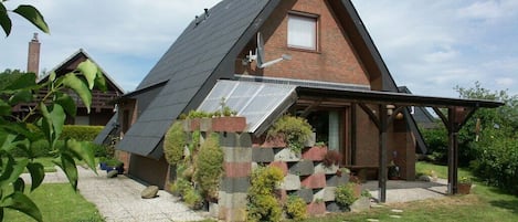 Ein modernes Haus mit Satteldach, Backsteinfassade und einer überdachten Veranda.