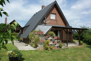 A modern house with a sloped roof, a brick exterior, and a covered porch. - Holiday home with 2 bedrooms (Wurster Nordseeküste)