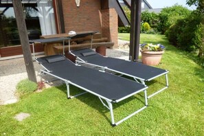 Two sun loungers with metal frames and black cushions, positioned on a grassy lawn. - Holiday home with 2 bedrooms (Wurster Nordseeküste)